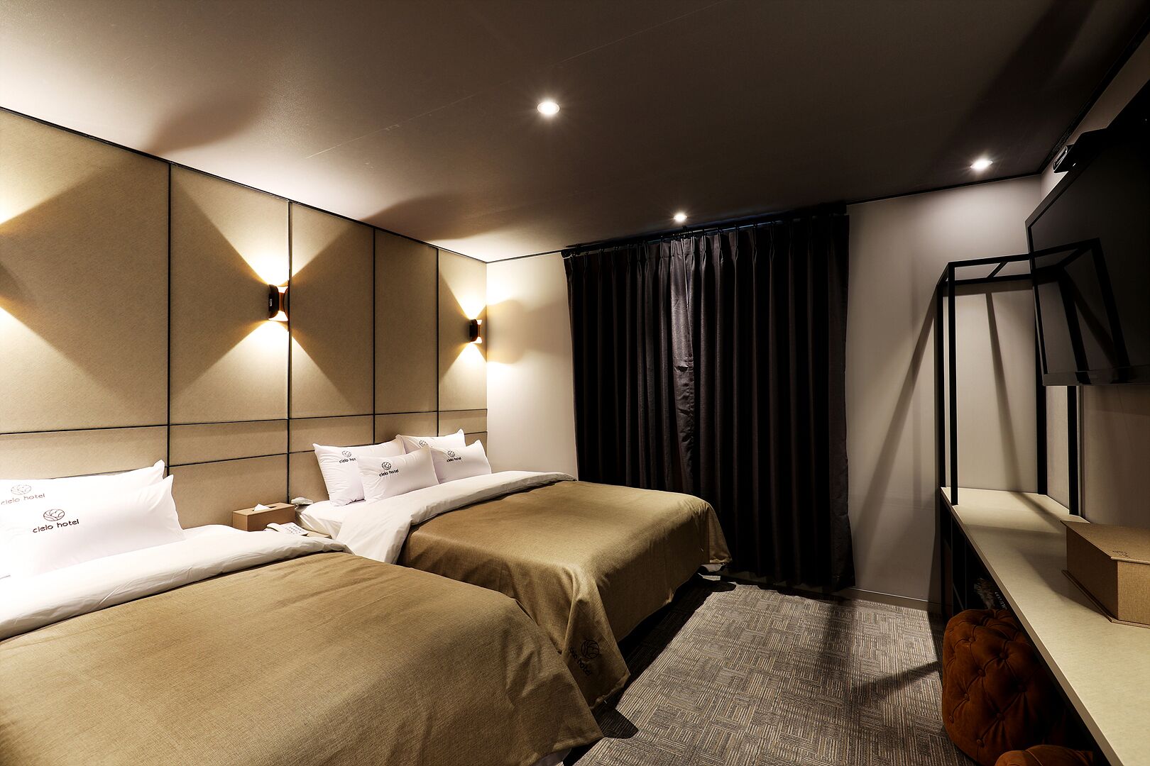 Una habitación de hotel moderna con dos camas, un escritorio y un espejo grande.