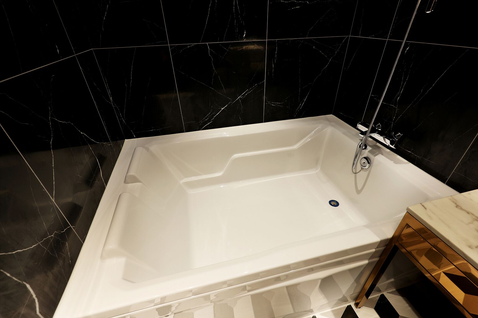 Une salle de bain moderne avec une baignoire blanche, des carreaux de marbre noir et un meuble-lavabo en bois.
