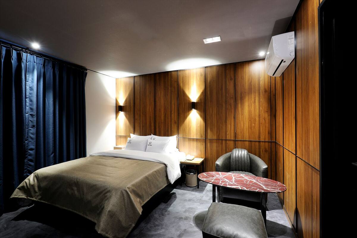 A modern hotel room with a bed, a small table, and a chair.