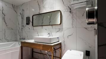 Un baño moderno con pared de mármol, un lavamanos, un espejo, un perchero para toallas, un inodoro y una ducha.
