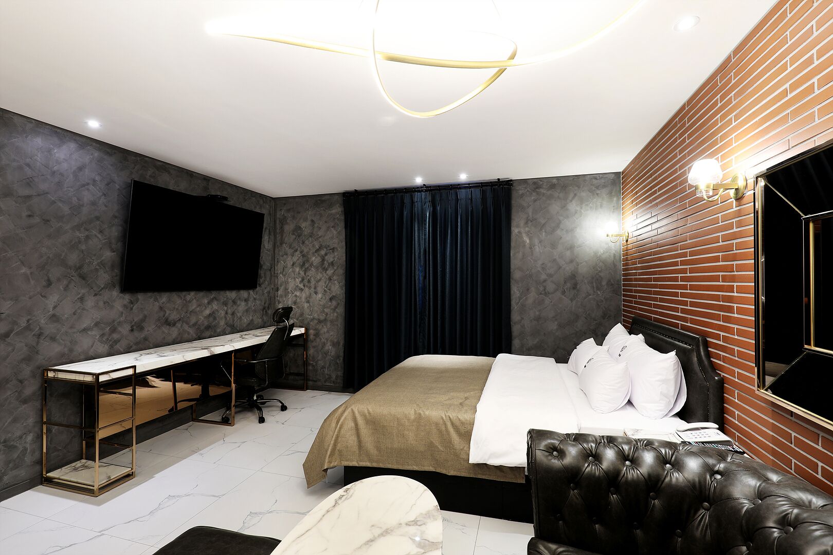 A modern bedroom with a bed, desk, and leather armchair.