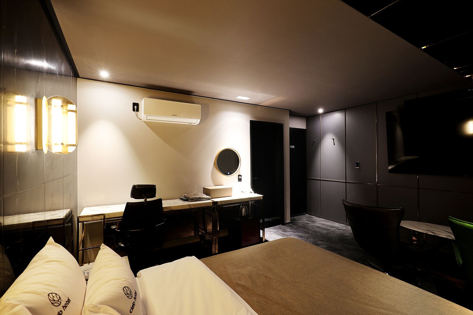 A modern hotel room with a bed, desk, chair, and a TV.