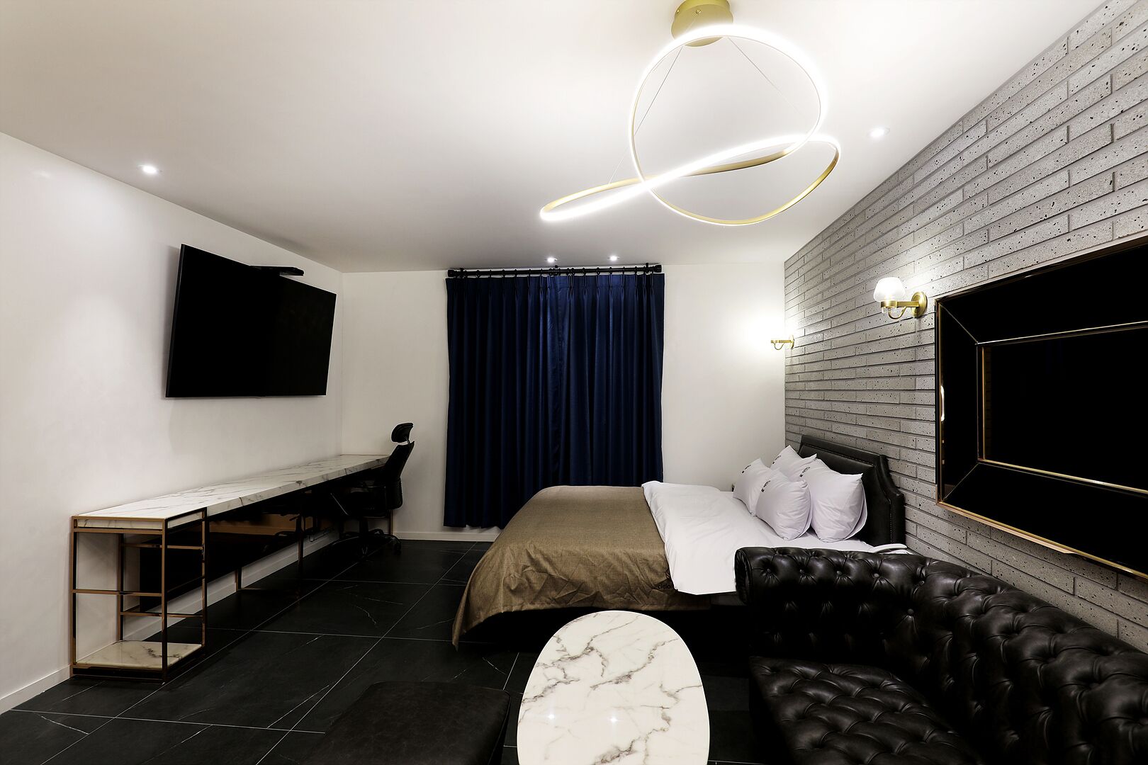 Ein modernes Hotelzimmer mit einem Bett, einer Ledersofa, einem Schreibtisch und einem Fernseher.