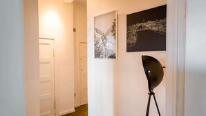A hallway with a white door, a framed black and white photo, and a black floor lamp. - Spacious 3 Bedroom Apartment Online Check-In (Berlin)