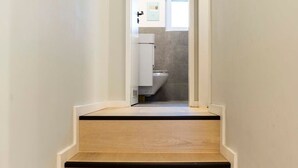 Een trap die leidt naar een badkamer met een toilet en wastafel.