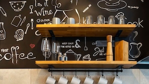 Een moderne keuken met een zwart aanrecht, een roestvrijstalen spoelbak en een houten plank met verschillende keukengerei.