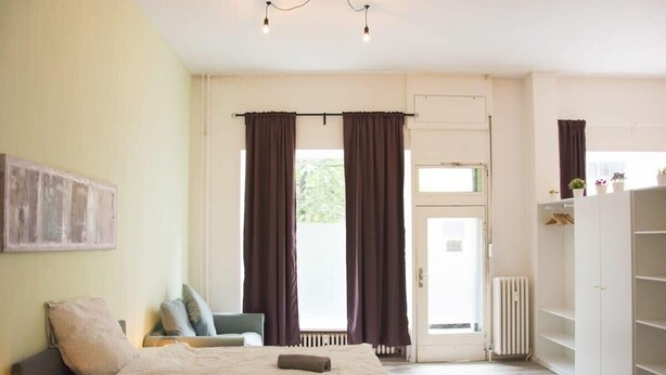 A bedroom with a bed, a chair, a radiator, and a wardrobe.
