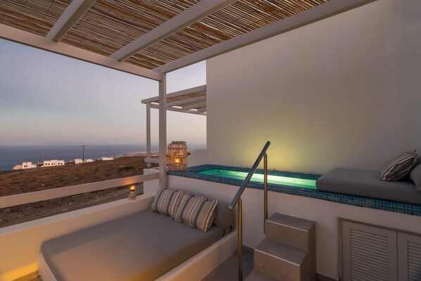 A balcony with a seating area, a small pool, and a view of the coastline.