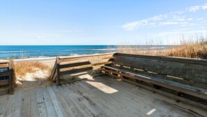 A wooden boardwalk leading to a beach with a bench. - Windjammer: Oceanfront, Shared Pool, Beach Access (Nags Head)