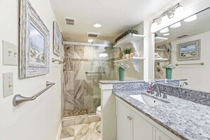 Un baño con ducha, lavamanos y espejo.