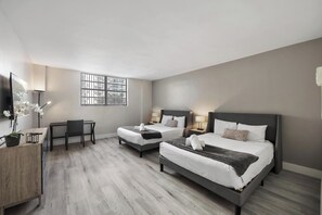 A hotel room with two beds, a desk, and a TV. - Two Bedroom Resort Suite with Pool and Gym (Hollywood)