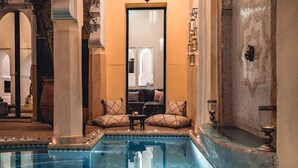 A luxurious indoor pool area with a seating arrangement and a clear view of the adjacent room. - Riad Ambre & Epices Marrakech (Marrakesh)