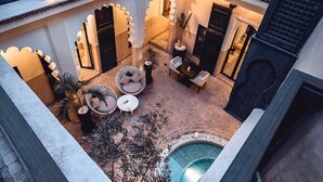 A courtyard with a pool, seating areas, and a view of the surrounding architecture. - Riad Ambre & Epices Marrakech (Marrakesh)