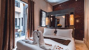 A hotel room with a large bed, a view of the outside, and a decorative mirror. - Riad Ambre & Epices Marrakech (Marrakesh)