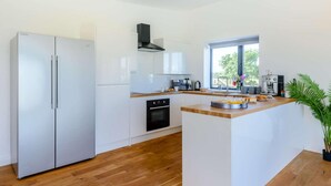 A modern kitchen with a central island, stainless steel appliances, and a view of the outdoors. - 2-bed Modern Bungalow - Outstanding Country Views (Harrogate)