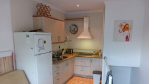 A compact kitchen with a refrigerator, sink, and cabinets. - Impeccable 1-bed House in Sayalonga (Sayalonga)