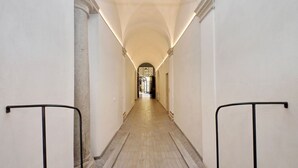 A corridor with a tiled floor, white walls, and a central archway at the end.