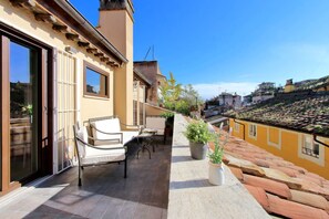 A balcony with outdoor furniture, a potted plant, and a view of a cityscape.