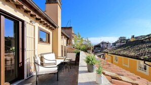 A balcony with outdoor seating, a potted plant, and a view of a cityscape.