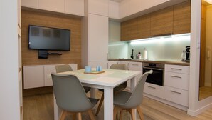 Une cuisine moderne dotée d’un téléviseur à écran plat, de meubles en bois et d’un coin repas avec des chaises et une table.