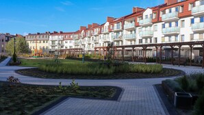 Un immeuble résidentiel doté de balcons, d’une aire de jeux et d’un chemin piétonnier dallé.