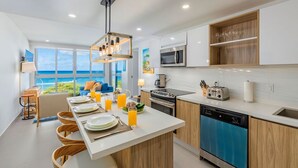 A modern kitchen with a large island, stainless steel appliances, and a view of the ocean. - Discover Ocean View Condo Living (Oranjestad)