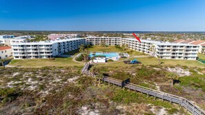 A large resort with multiple buildings, a central pool, and a boardwalk leading to the pool area.