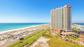 Ein Hochhaus-Hotel mit mehreren Balkonen mit Blick auf Strand und Meer.