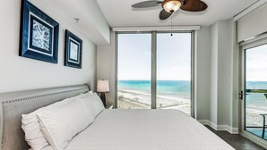 Une chambre d’hôtel avec un grand lit, un ventilateur de plafond et vue sur la plage.