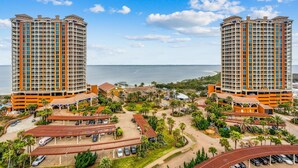 A high-rise hotel with multiple balconies, a parking area, and a view of the ocean. - P1-1105 2B Island View @ Portofino (Pensacola Beach)