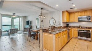 A modern kitchen with granite countertops, wooden cabinets, and stainless steel appliances. - P1-1105 2B Island View @ Portofino (Pensacola Beach)