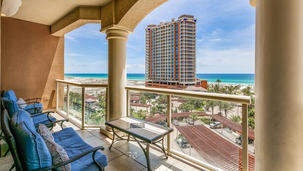 Een balkon met uitzicht op een hoog hotel en het strand.