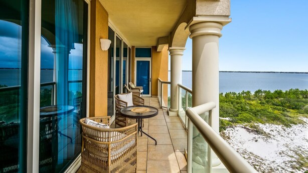 Un balcon doté de meubles en osier et offrant une vue sur la mer.