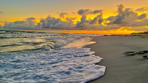 A beach with waves crashing onto the shore and a sunset in the background. - Great for families! Portofino 2-1908 (Pensacola Beach)