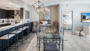 A modern kitchen with a bar area, a dining table with chairs, and a large mirror. - 2B Gulf Front w Private Terrace/Tower 3! (Pensacola Beach)
