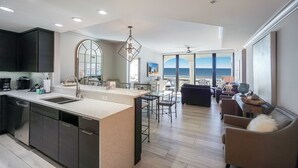 A modern kitchen with a large island, a dining area with a view of the ocean, and a living room with a view of the ocean. - 2B Gulf Front w Private Terrace/Tower 3! (Pensacola Beach)