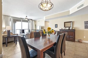 Un vaste espace dédié à la salle à manger, avec une table en bois, des chaises et un vase rempli de tournesols.
