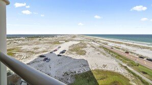 Blick vom Balkon auf einen Strand mit Parkplatz und Straße.