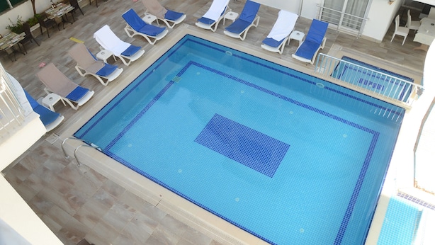 A swimming pool with lounge chairs and a tiled deck area. - Honor A Pansiyon Side (Manavgat)