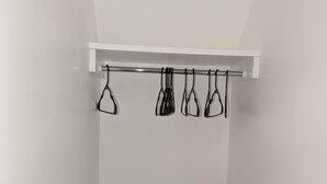 Een witte kast met een stang waarop meerdere zwarte kledinghangers hangen.