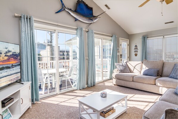 Relax in this stylish living room with a balcony offering views of the surrounding area, featuring a sofa, coffee table, and TV.