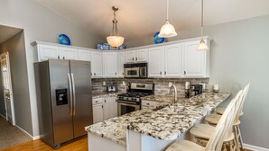 A kitchen with white cabinets, stainless steel appliances, a granite countertop, and wooden chairs. - 1 Block to Beach and Boardwalk "Between the Piers" (Wildwood)