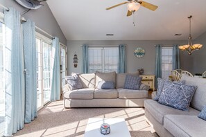 Relax in this inviting living room with a beige sofa, coffee table, and ceiling fan.