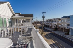 Enjoy the view from this balcony with two chairs and a table overlooking a charming street lined with houses.