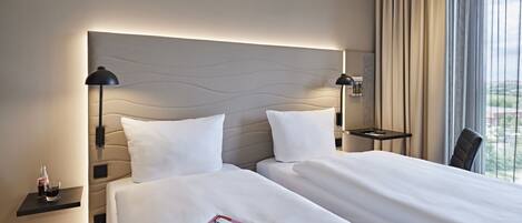 A hotel room with two beds, a nightstand with a bottle of Coca-Cola, a glass, and a magazine.