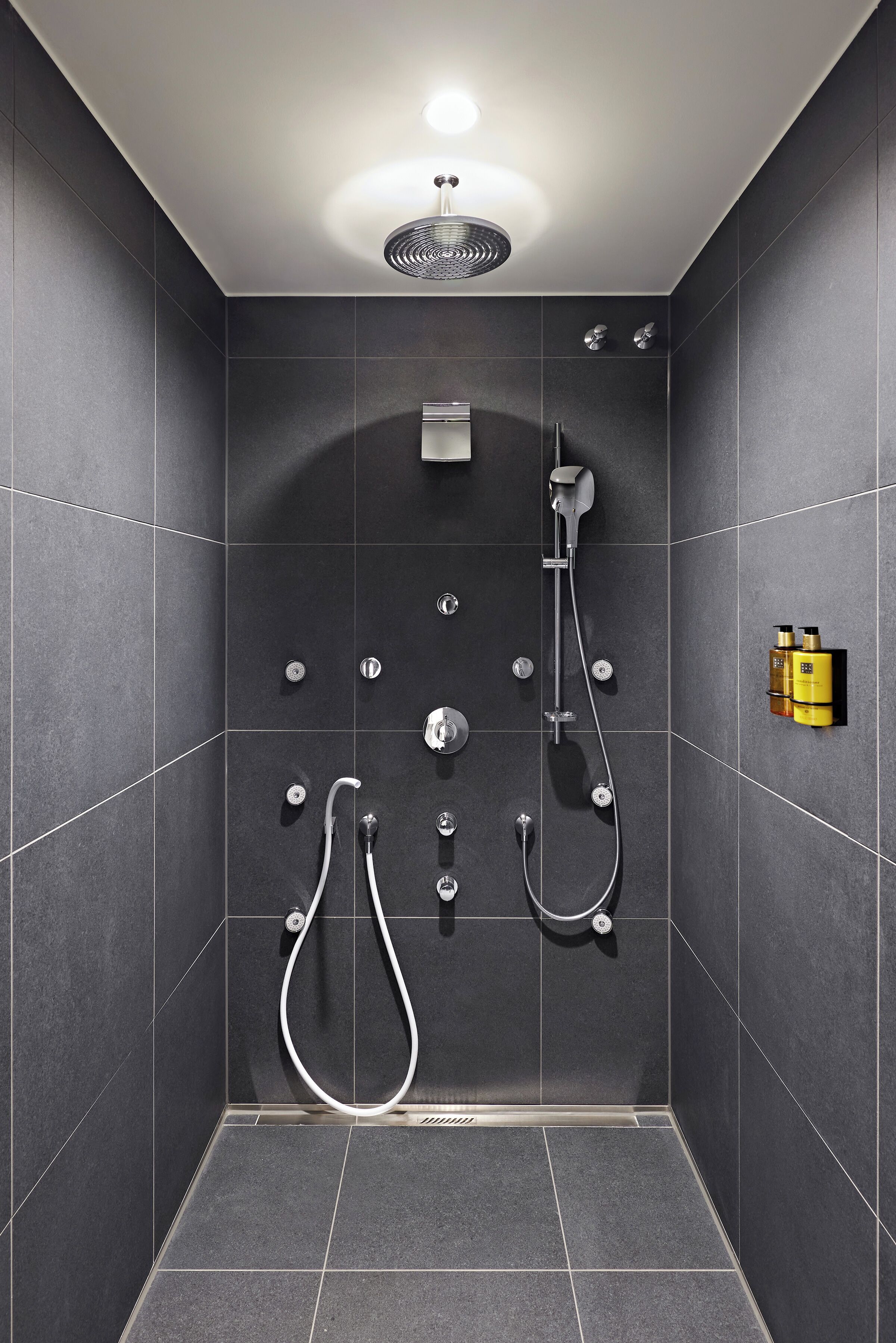 A modern shower with multiple controls and a handheld showerhead.