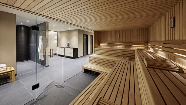 Una sauna con bancos de madera y una pared de vidrio que da a un baño.