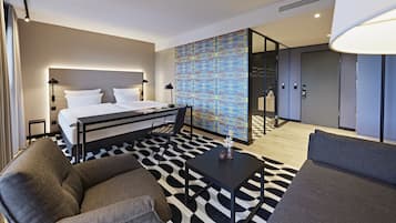 Et moderne hotelværelse med seng, skrivebord, sofa og et tæppe med mønster.