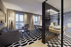 Enjoy a city view from the large window in this stylish room, featuring a sofa, dining table, and modern bathroom with separate shower area.