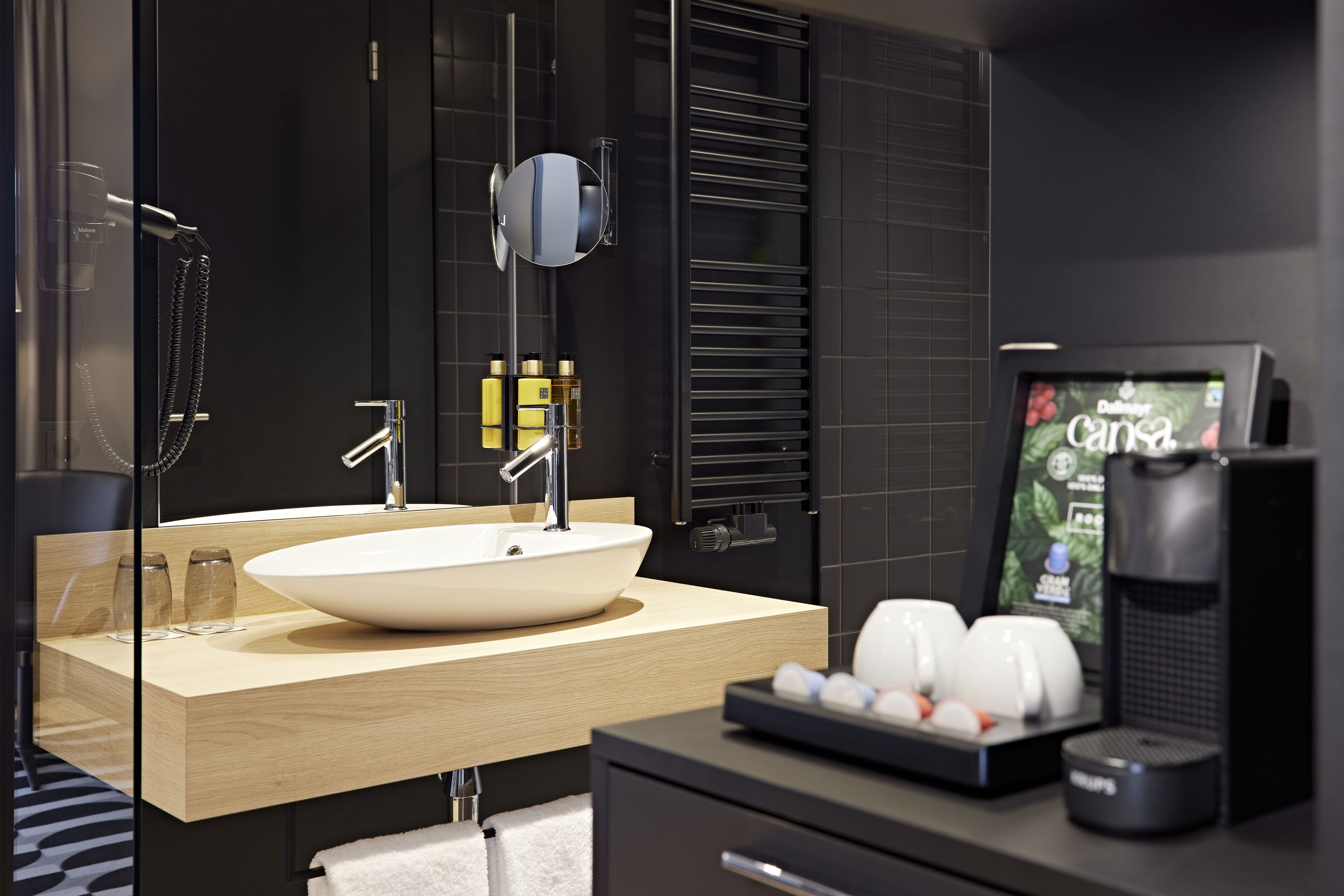 Une salle de bain moderne avec un grand lavabo, un miroir, une douche et une machine à café.